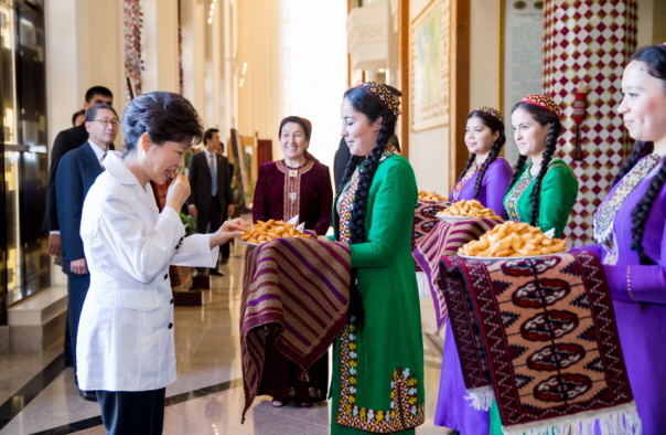  박근혜 대통령이 20일 투르크메니스탄 아쉬하바드 국제공항에 도착, 문화풍습에 따라 전통 빵인 '초레크'를 맛보고 있다. (사진: 청와대)