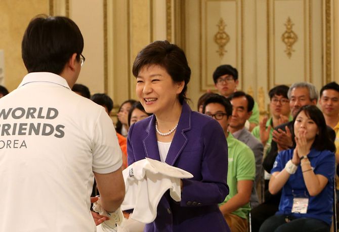 박근혜 대통령(가운데)이 31일 청와대 영빈관에서 열린 '2013 WFK(World Friends Korea) 해외 봉사단 발대식'에서 한 참가자로부터 기념티셔츠를 전달받고 있다. (사진: 청와대)